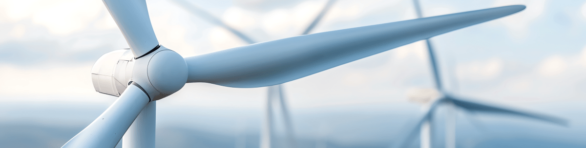 Close-up of a white wind turbine with large blades, set against a blurred background of additional turbines and a cloudy sky. The image emphasizes renewable energy and clean technology. by Standex Detect