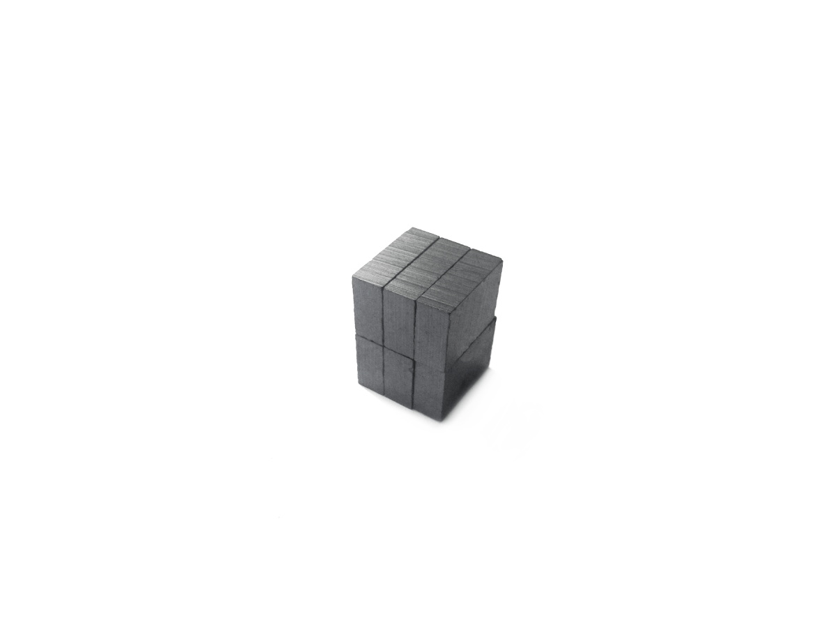 A small cube made of multiple stacked gray rectangular Hard Ferrite Magnets, arranged neatly against a plain white background. by Standex Detect